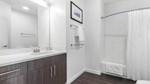 ein weißes Badezimmer mit einem Waschbecken und einem Spiegel in der Unterkunft Landing Modern Apartment with Amazing Amenities (ID5464X62) in Weatogue
