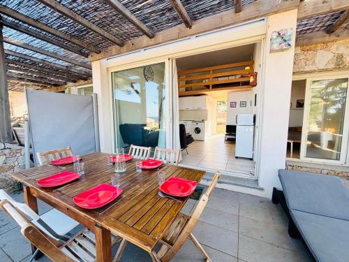 - une table en bois avec des plaques rouges sur la terrasse dans l'établissement Appartement Libeccio 2 LUMIO, à Lumio