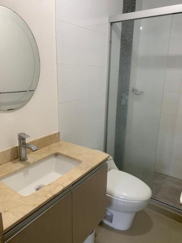 uma casa de banho com um WC, um lavatório e um espelho. em Cómodo apto excelente ubicación em Barranquilla
