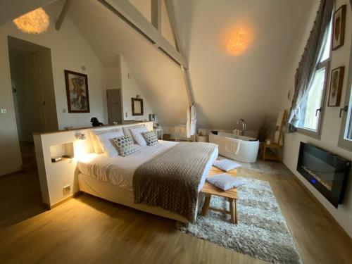 een slaapkamer met een bed, een bad en een wastafel bij L'Orée du Mont in Pontorson