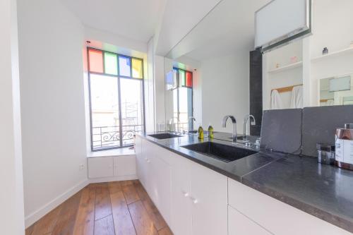 une cuisine blanche avec un évier et une fenêtre dans l'établissement Terrasse de Bellecour - Lyon 2 Plein Centre, à Lyon
