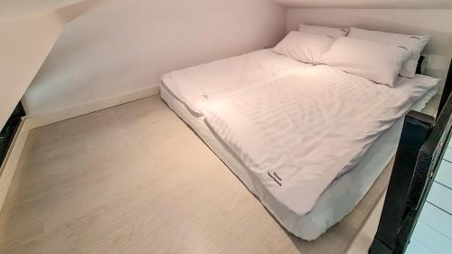 Cama en habitación pequeña con sábanas y almohadas blancas en Dream Apartments 2B, en Oświęcim