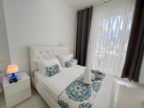een slaapkamer met een wit bed en een raam bij ATLANTICO SUITES - ROOFTOP POOL, BARS & BEACH CLUB in Punta Cana