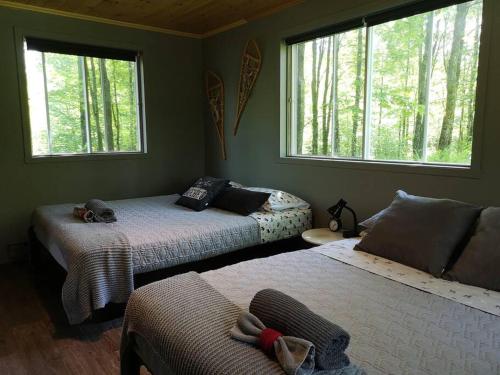 a bedroom with two beds and two windows at Chalet Chic Shack - Un endroit paisible in Frampton