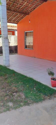 een oranje gebouw met een veranda en een raam bij Paraíso a Beira Mar in Praia Da Caueira