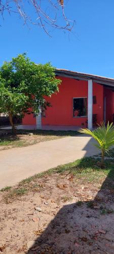 een rood gebouw met een palmboom ervoor bij Paraíso a Beira Mar in Praia Da Caueira