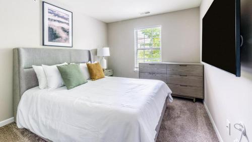 1 dormitorio con 1 cama blanca y TV en Landing Modern Apartment with Amazing Amenities (ID4377X11), en Naperville