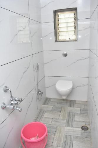 a white bathroom with a toilet and a window at HOTEL SAI VISHVA KARMA in Shirdi