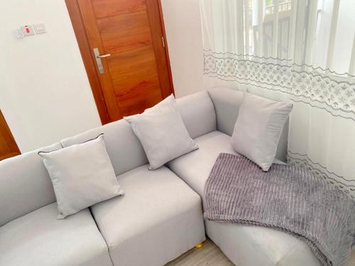 un divano bianco con 4 cuscini in una stanza di LuckySmallie 1-Bed Apartment in Goba Dar es Salaam a Dar es Salaam