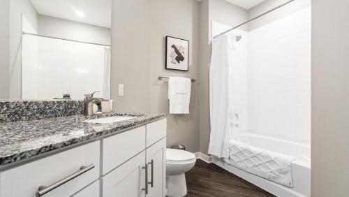 y baño blanco con aseo y ducha. en Landing Modern Apartment with Amazing Amenities (ID8082X78), en Chapel Hill