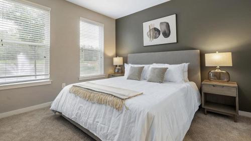 a bedroom with a large white bed and two windows at Landing Modern Apartment with Amazing Amenities (ID8082X78) in Chapel Hill