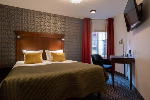 a hotel room with a bed and a desk and a television at ProfilHotels Opera in Gothenburg