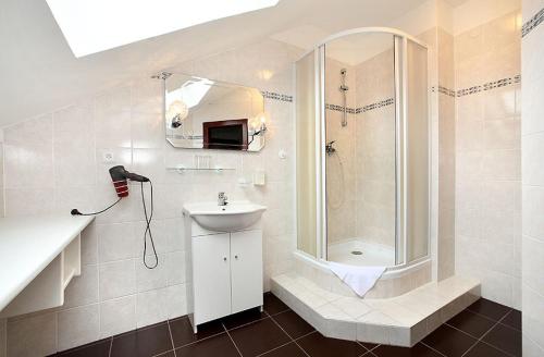 a white bathroom with a shower and a sink at HOTEL RAJSKY in Český Krumlov