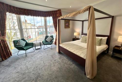 a bedroom with a canopy bed and chairs and a window at The Windmill Hotel in Lincolnshire
