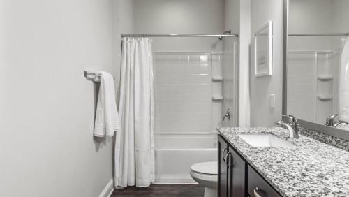 a white bathroom with a shower and a toilet at Landing Modern Apartment with Amazing Amenities (ID8773X70) in Matthews