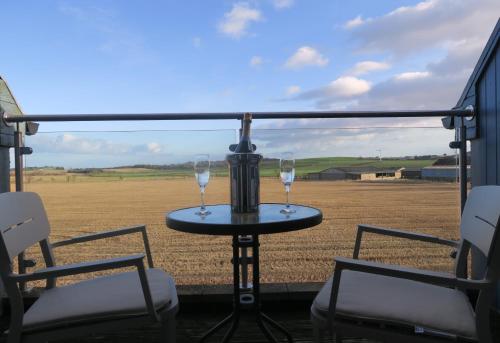 two wine glasses sitting on a table in front of a field at The Inn At Lathones in St. Andrews