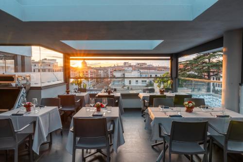 a restaurant with white tables and chairs and windows at Twentyone Hotel in Rome