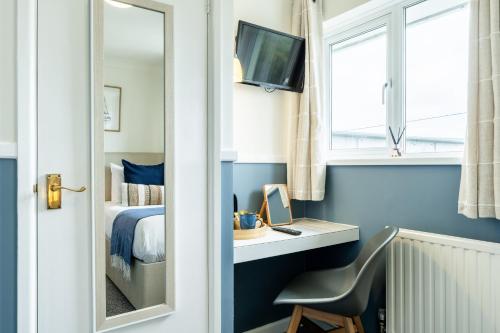 a bedroom with a bed and a desk with a mirror at Inn For All Seasons in Redruth