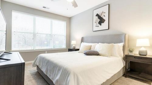 ein Schlafzimmer mit einem weißen Bett und einem Fenster in der Unterkunft Landing Modern Apartment with Amazing Amenities (ID8112X15) in Chapel Hill