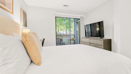 um quarto branco com uma cama grande e uma televisão em Landing Modern Apartment with Amazing Amenities (ID6735X37) em Greensboro