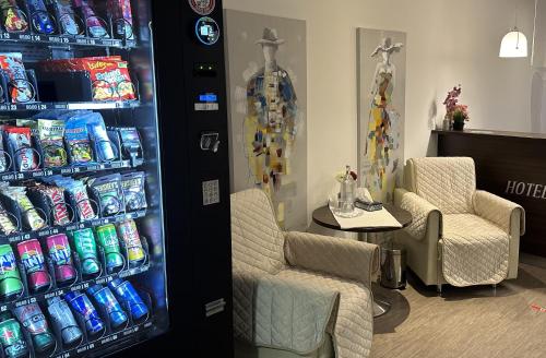 a soda vending machine with two chairs and a table at Hotel Efcannos Dornberg Carree in Vechelde