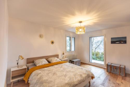 a bedroom with a bed and two windows at Le toit de Chardonne - Entre Alpes et lac Léman in Chardonne