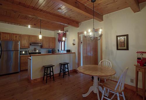a kitchen with a table and a table and chairs at Chalet des bouleaux in Nominingue