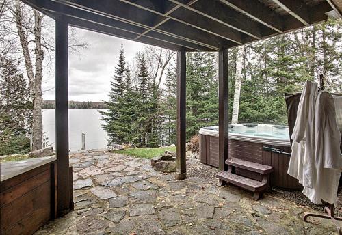 a large outdoor bath tub with a view of a lake at Chalet des bouleaux in Nominingue