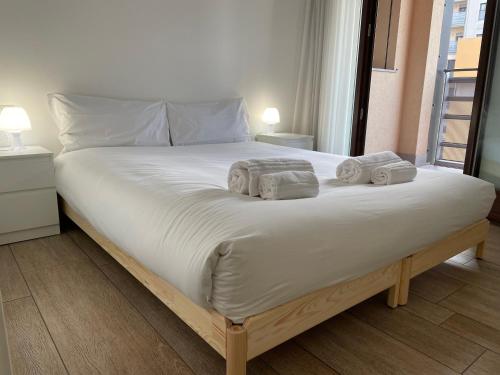 a large white bed with two towels on it at Hospitami Apartment - 15 min Duomo Milano in Milan
