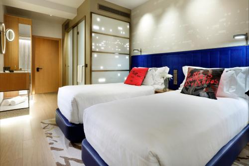 a hotel room with two beds and a bathroom at Hard Rock Hotel Madrid in Madrid