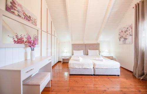 a white bedroom with a bed and flowers on the wall at Zante Sun I - Getaway Villa! in Zakynthos