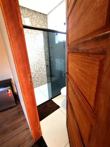 a bathroom with a wooden door and a toilet at Pousada Mirante Das Serras Ibicoara-BA in Ibicoara