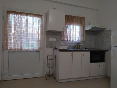 a kitchen with white cabinets and a white door at Creta Irini's Rooms3 in Tympáki