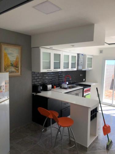 Casa de Playa في بلاليا أونيون: مطبخ مع منضدة بيضاء وكراسي برتقالية