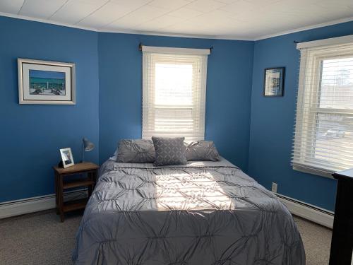 ein blaues Schlafzimmer mit einem Bett und zwei Fenstern in der Unterkunft Bradley Beach Cozy Retreat in Bradley Beach