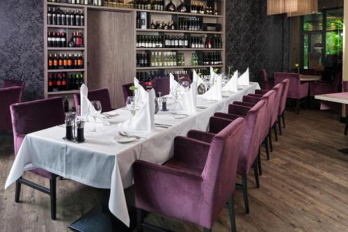 a long table in a restaurant with purple chairs at Steigenberger Parkhotel Braunschweig in Braunschweig