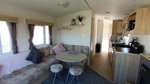 a living room with a couch and a table at Serena Little Escape, West Sands Holiday in Selsey