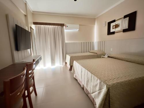 Habitación de hotel con 2 camas, escritorio y TV. en Spazzio Diroma, C - Acesso Ao Acqua Park en Caldas Novas