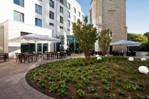 a courtyard with tables and chairs and umbrellas at Steigenberger Parkhotel Braunschweig in Braunschweig
