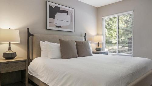 um quarto com uma cama branca, 2 candeeiros e uma janela em Landing Modern Apartment with Amazing Amenities (ID9191X62) em Marietta