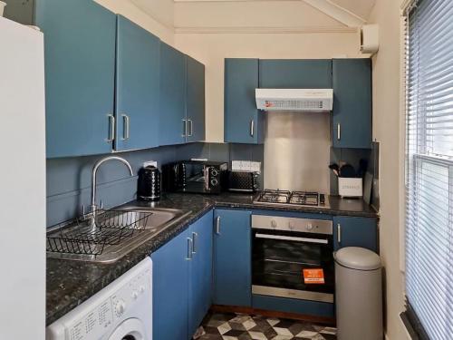 a blue kitchen with a sink and a dishwasher at Gravesend 2 bedroom Apartment, 2 mins walk to Station in Kent