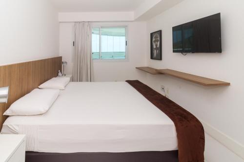 1 dormitorio con 1 cama blanca grande y TV de pantalla plana en Flat Ocean View III, en Río de Janeiro