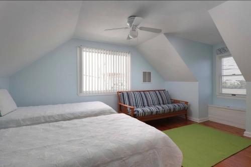a bedroom with a bed and a couch and a ceiling fan at Island Time- beautifully renovated bay view home in Seaside Heights