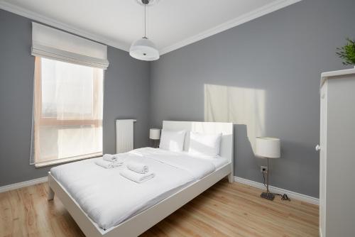 Un dormitorio blanco con una gran cama blanca y una ventana en Duńska Chic Apartment, en Szczecin