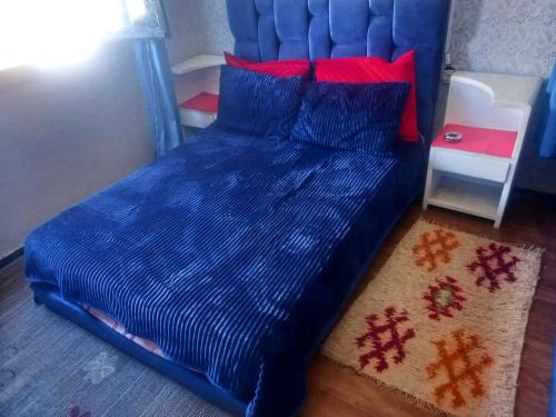 1 cama con edredón azul y almohadas rojas en Studio prestige N1 pieds sur Mer en Rabat