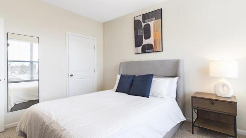 ein weißes Schlafzimmer mit einem Bett und einem Spiegel in der Unterkunft Landing Modern Apartment with Amazing Amenities (ID8982X42) in Indianapolis