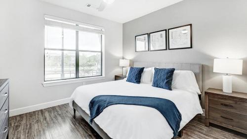 1 dormitorio blanco con 1 cama grande con almohadas azules en Landing Modern Apartment with Amazing Amenities (ID4250X31), en Frisco