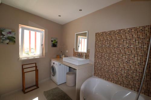 a bathroom with a tub and a sink and a washing machine at Apartamento Vista Marina in Lagos