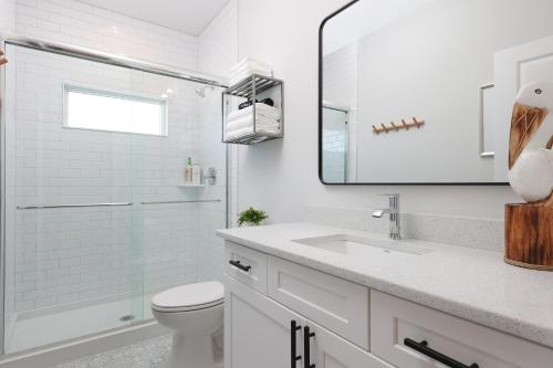 a white bathroom with a toilet and a sink at The Pelican's Perch: New Build in Seaside Heights