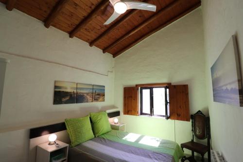 Un dormitorio con una cama con almohadas verdes y una ventana en Casa Azul, en Cumeada